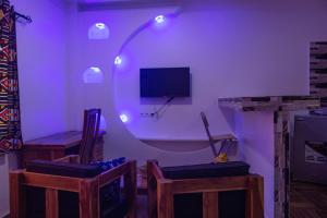 a room with a purple room with chairs and a tv at Les perles du bonheur Nyékonakpoé in Lomé