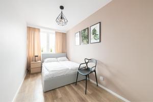 um quarto branco com uma cama e uma cadeira em Prime Apartments - Oliva View em Gdansk
