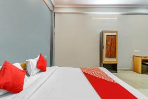 1 dormitorio con 1 cama con almohadas rojas y blancas en Orphic Inn Near Munshi Pulia Metro Station, en Chinhat