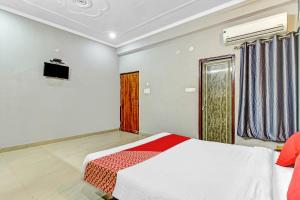 1 dormitorio con 1 cama con colcha roja y blanca en Orphic Inn Near Munshi Pulia Metro Station, en Chinhat
