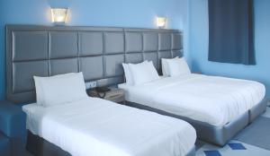 two beds in a hotel room with white sheets at Hôtel Mandy in Tétouan