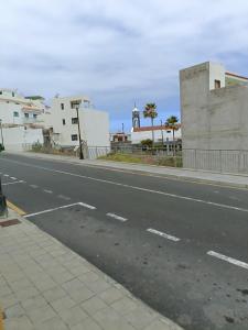 una calle urbana vacía con edificios y una carretera en vista al mar. en Caleta de Interián
