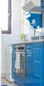 a blue kitchen with a stove and a sink at Cozy flower apartment in Vranje