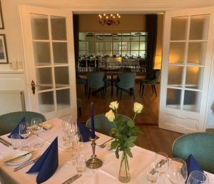 a dining room with a table with blue napkins and flowers at Hotel Ærøhus in Ærøskøbing