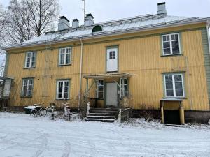 una casa amarilla con nieve delante en Yksiö+autopaikka/Small apt.+free parking, en Hyvinkää