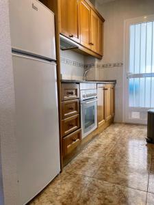 La cuisine est équipée d'un réfrigérateur blanc et de placards en bois. dans l'établissement La Ciñuelica R14 First Floor Apartment L126, à Orihuela