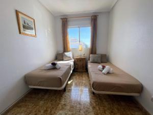- 2 lits dans une petite chambre avec fenêtre dans l'établissement La Ciñuelica R14 First Floor Apartment L126, à Orihuela