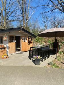 a patio with a table and an umbrella at Caravan op Camping t Kopske in Den Hout in Den Hout