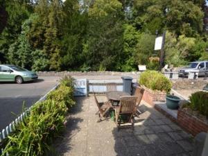 a patio with a table and chairs next to a street at Quince Cottage in Ventnor +2 photos