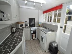 a kitchen with a stove and a washer and dryer at Quince Cottage in Ventnor