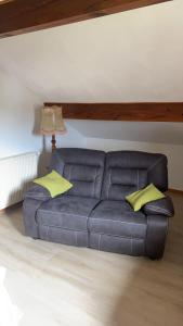 - un canapé en cuir dans le salon avec des oreillers jaunes dans l'établissement Au Grés du Vent, à Ruy
