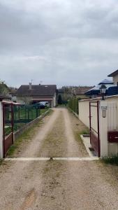 a dirt road with a gate and some buildings at Au Grés du Vent in Ruy