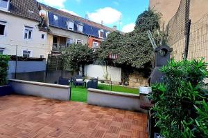 een achtertuin met een hek en een bakstenen patio bij La cachette - Maison centre in Mulhouse