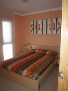 a bedroom with a bed with a striped comforter at Apartamento a pie de playa - Mojacar in Mojácar