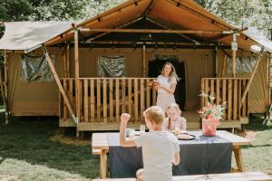 a woman and two children in front of a yurt at Vakantiepark Dierenbos in Vinkel