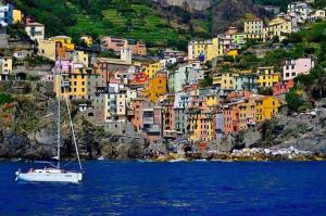 a boat in the water in front of a city at Appartamento chic Riomaggiore 5 Terre in Riomaggiore