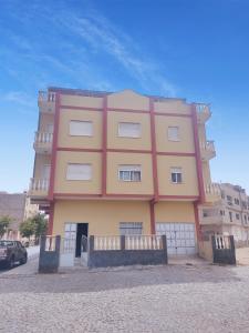 ein großes rosa und gelbes Gebäude auf einer Straße in der Unterkunft Apartamento acolhedor com vista para o Monte Cara in Mindelo