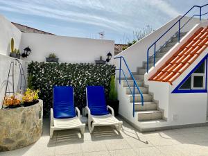 Duas cadeiras azuis sentadas num pátio ao lado das escadas em Casa dos Montes em Alvor