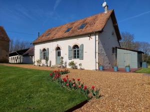 ein weißes Haus mit roten Tulpen davor in der Unterkunft La Ferme Neuve in Fillé