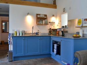 uma cozinha com armários azuis e um lavatório em An Airigh em Dunan