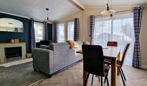 a living room with a couch and a dining room table at Stunning Lodge With Large Decking At Azure Seas In Suffolk Ref 32109og in Lowestoft