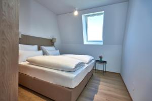 Schlafzimmer mit einem Bett mit weißer Bettwäsche und einem Fenster in der Unterkunft Aparthotel Bad Radkersburg in Bad Radkersburg