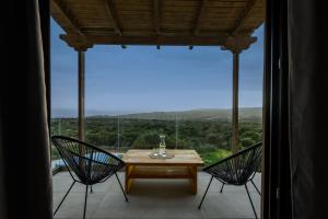 a table and two chairs in a room with a large window at Hilltop Kefalonia in Argostoli