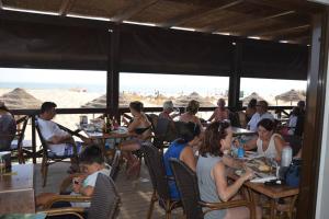 un grupo de personas sentadas en mesas en la playa en Luxury Apartment in Marina de Isla Canela- Beach Front, en Huelva