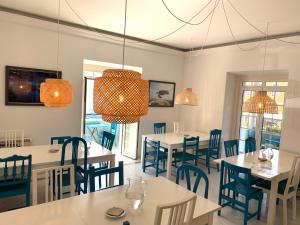 a dining room with white tables and blue chairs at Impact Beach House in Estoril