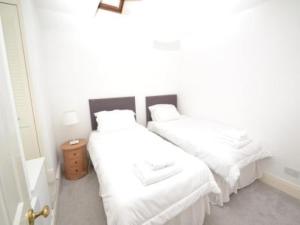 a bedroom with two beds with white sheets at Quince Cottage in Ventnor