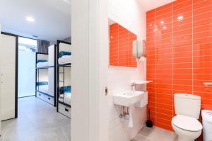 y baño con azulejos de color naranja, aseo y lavamanos. en LOGUNE ROOMS, en Vitoria-Gasteiz