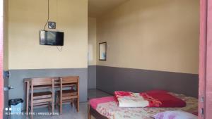 um quarto com uma cama, uma mesa e uma televisão em Tengger Indah Bromo by ABM em Bromo