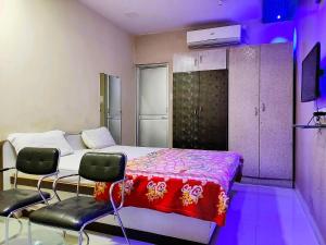 STAYMAKER Madhuwan Heights في Bokāro: غرفة نوم فيها سرير وكرسيين