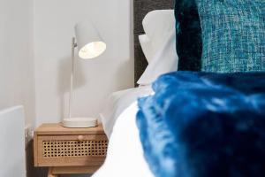 a bed with a blue pillow and a lamp on a night stand at Swanky city centre apartment in Lincolnshire