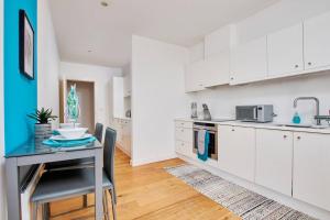 a kitchen with white cabinets and a table and chairs at Swanky city centre apartment in Lincolnshire