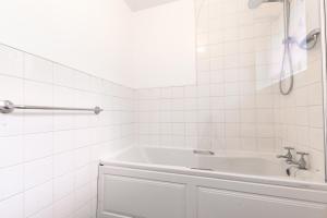 a white bathroom with a tub and a sink at Deepdene Close in Reading