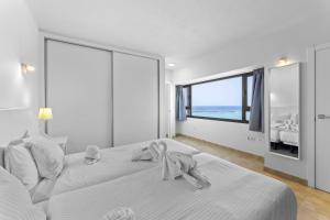 a white bedroom with a large bed and a large window at Apartamentos Arrecife Playa in Arrecife