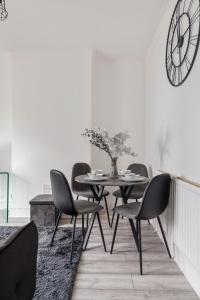 une salle à manger avec une table, des chaises et une horloge dans l'établissement Beautifully Modern 2-Bed Apartment w/garden, à Londres