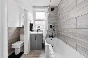 a bathroom with a tub and a toilet and a sink at Beautifully Modern 2-Bed Apartment w/garden in London