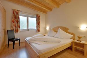 een slaapkamer met een bed met een stoel en een raam bij Wildauhof in Fügenberg