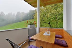 een houten tafel en stoelen op een veranda met een raam bij Wildauhof in Fügenberg