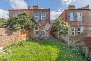 a brick house with a fence in front of it at Beautifully Modern 2-Bed Apartment w/garden in London