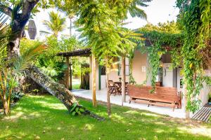 eine Holzbank in einem Garten mit Bäumen in der Unterkunft Vila Nativa Caraíva in Caraíva