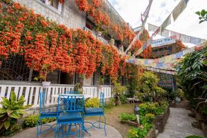 a garden with blue chairs and red flowers on a building at Hotel Yeti in Pokhara