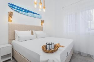 een witte slaapkamer met een bed en een dienblad met kaarsen bij Alpha & Omega in Karpathos