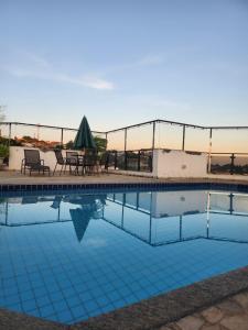 Una piscina con una mesa y sillas al lado. en AGUAS DE SÃO PEDRO VIP, en Águas de São Pedro