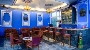 a restaurant with blue walls and a bar with tables and chairs at Hotel Kalyan in Jaipur