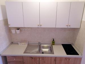 a kitchen with a sink and white cabinets at Apartment Suzie Q - Intermezzo with sea view in Rabac