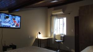 1 dormitorio con 1 cama y TV en la pared en Pousada Cusco - no Centro Jaraguá do Sul - Sem Estacionamento en Jaraguá do Sul