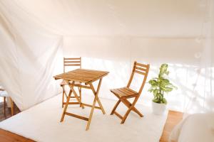 two chairs and a wooden table in a room at Kabaceira Glamping in Atalaia